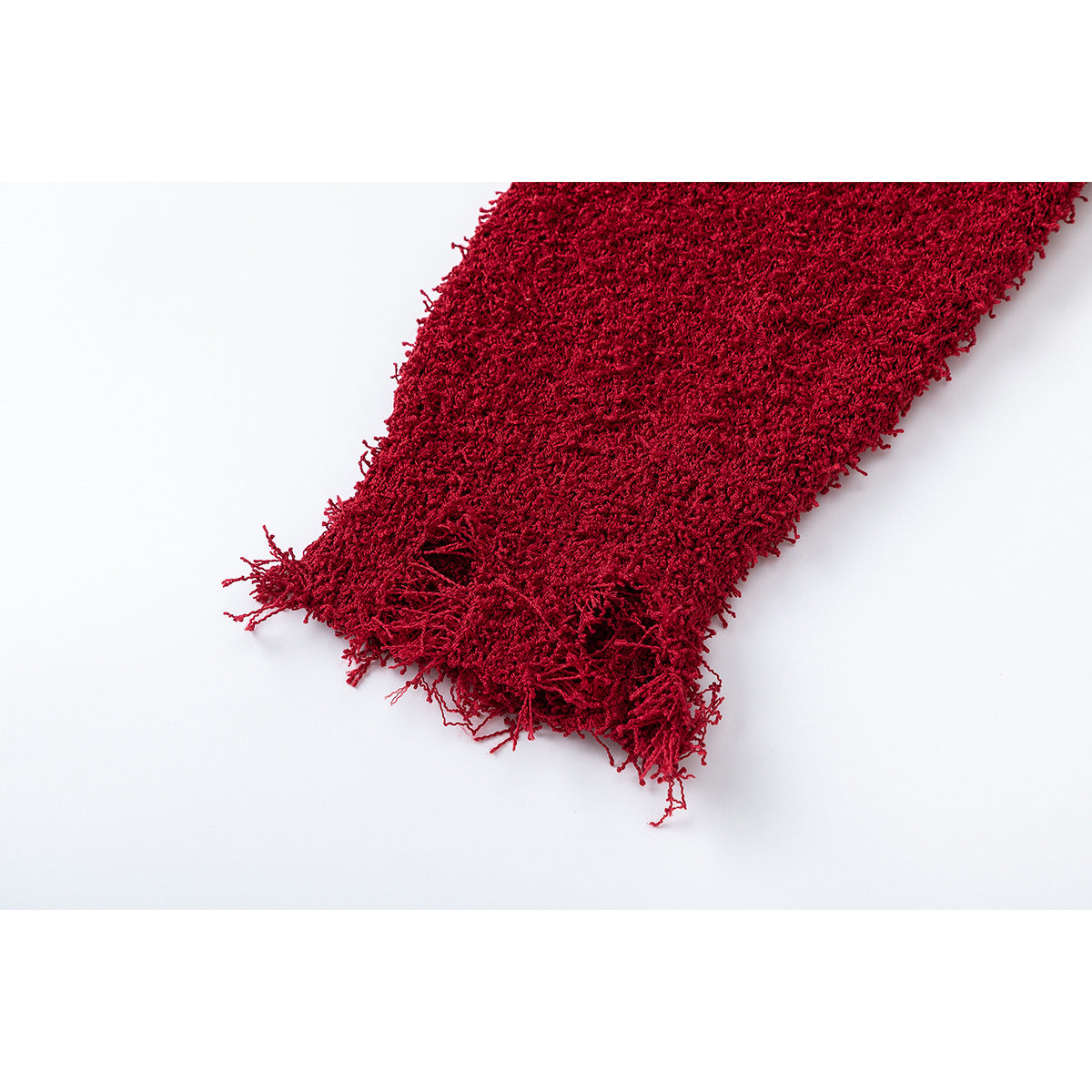 Close-up of the deep red scarf's shaggy weave and loose fringe at the end.