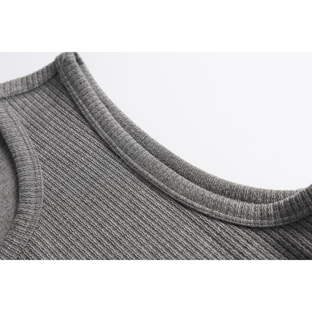 Close-up of the gray ribbed tank top's rounded neckline, shoulder seam, and armhole.