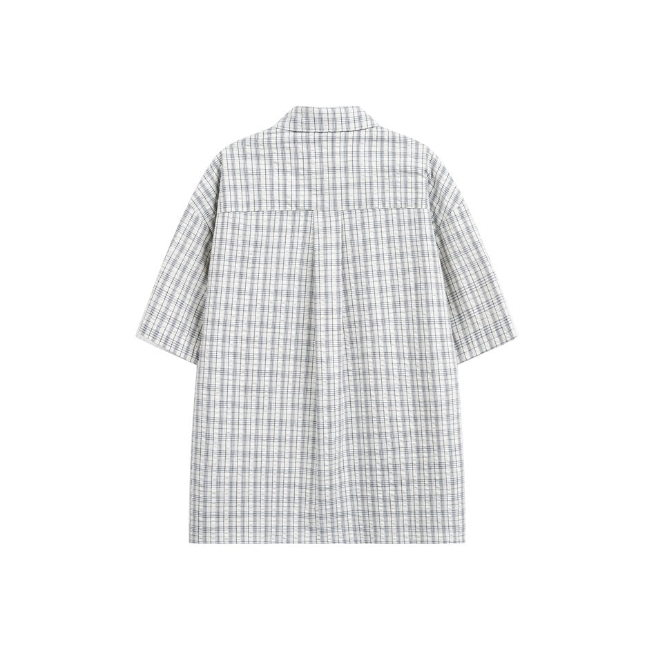 Back view of a white and blue plaid short-sleeve shirt, showing a yoke and pleat.