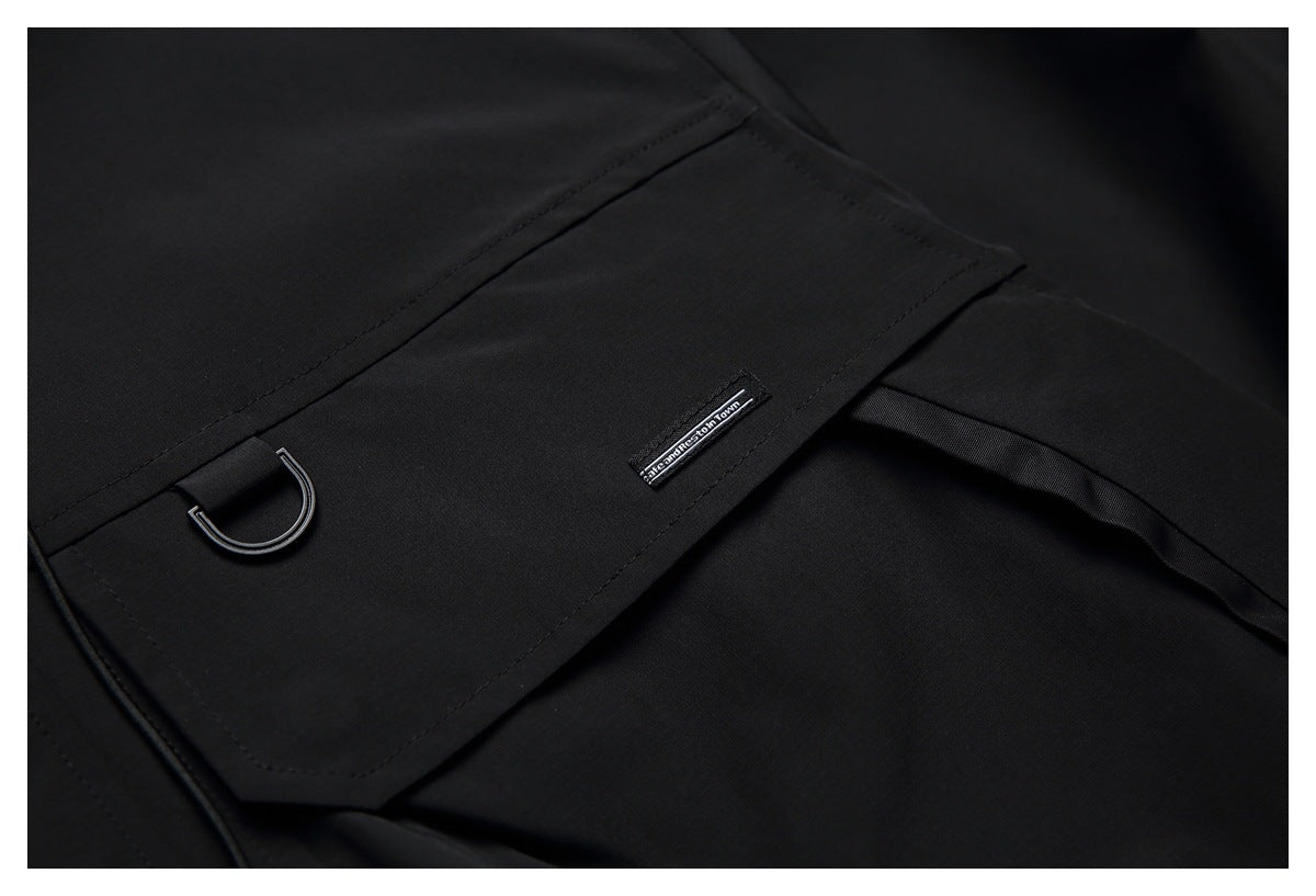 Close-up of a black garment pocket with a metal D-ring and a small sewn label.