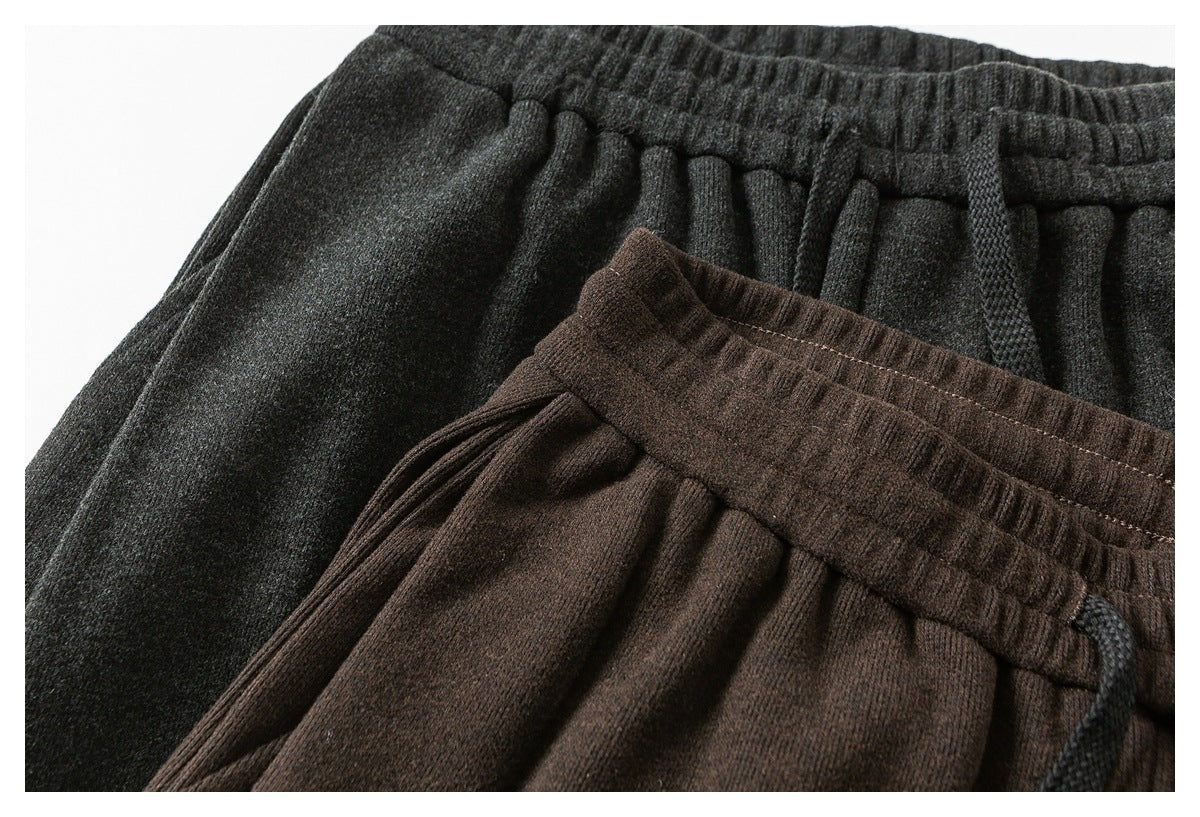 Close-up of charcoal and dark brown pants showing elastic waistbands, gathered fabric and drawstrings.