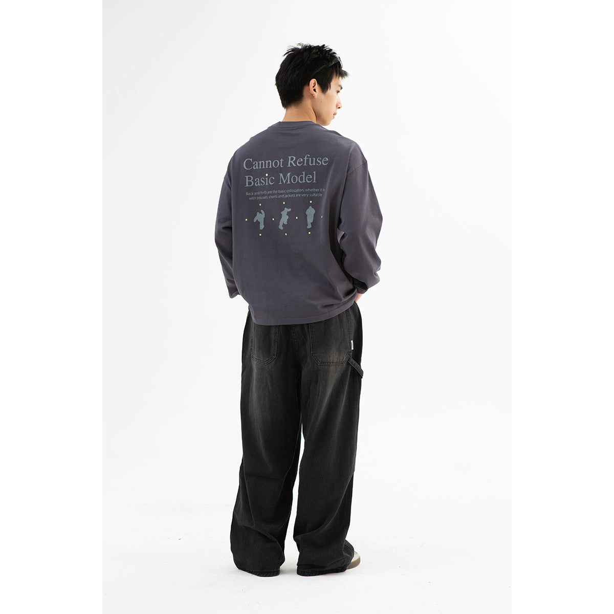 Model wearing a charcoal long-sleeve shirt with a large back graphic and black wide-leg pants, shown from behind.