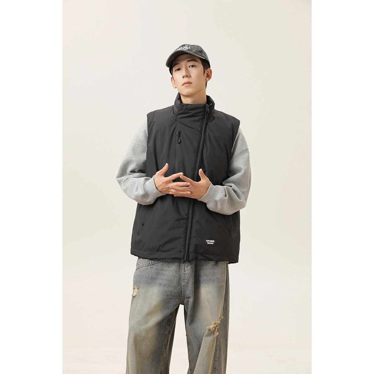 Front view of a model wearing a black zip vest over a gray sweatshirt.