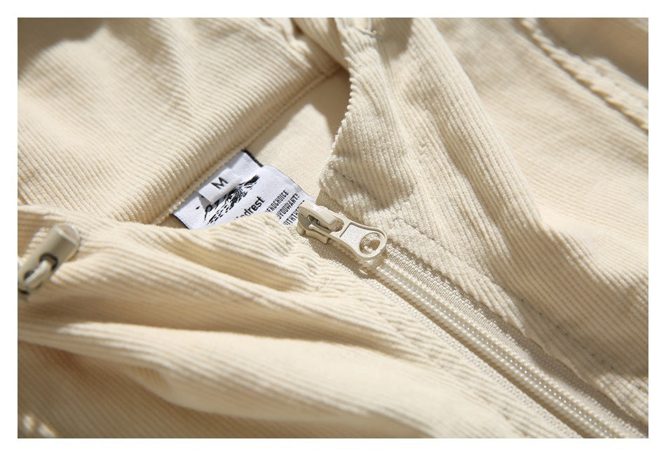 Close-up of a cream ribbed garment showing its zipper, folded collar, and sewn-in size label.