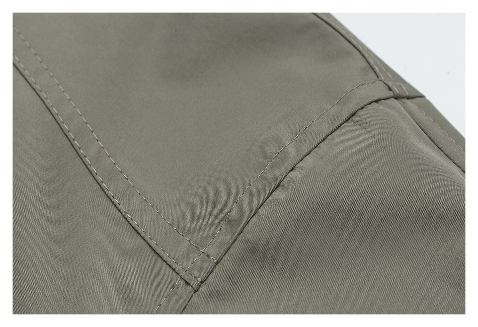 Close-up of stitched panel seams on olive-gray garment fabric.