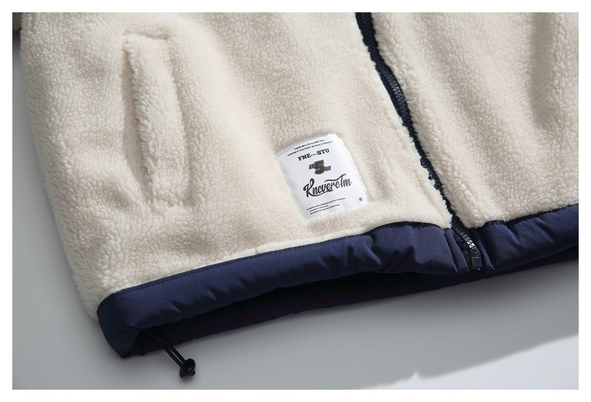 Close-up of the lower front of a cream sherpa jacket, showing a pocket, sewn label, zipper, and navy hem.