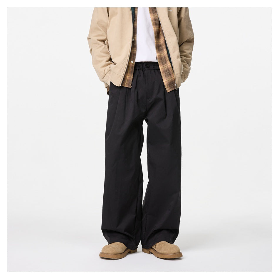Front view of a model wearing black wide-leg trousers with a gathered waist and front pleats.