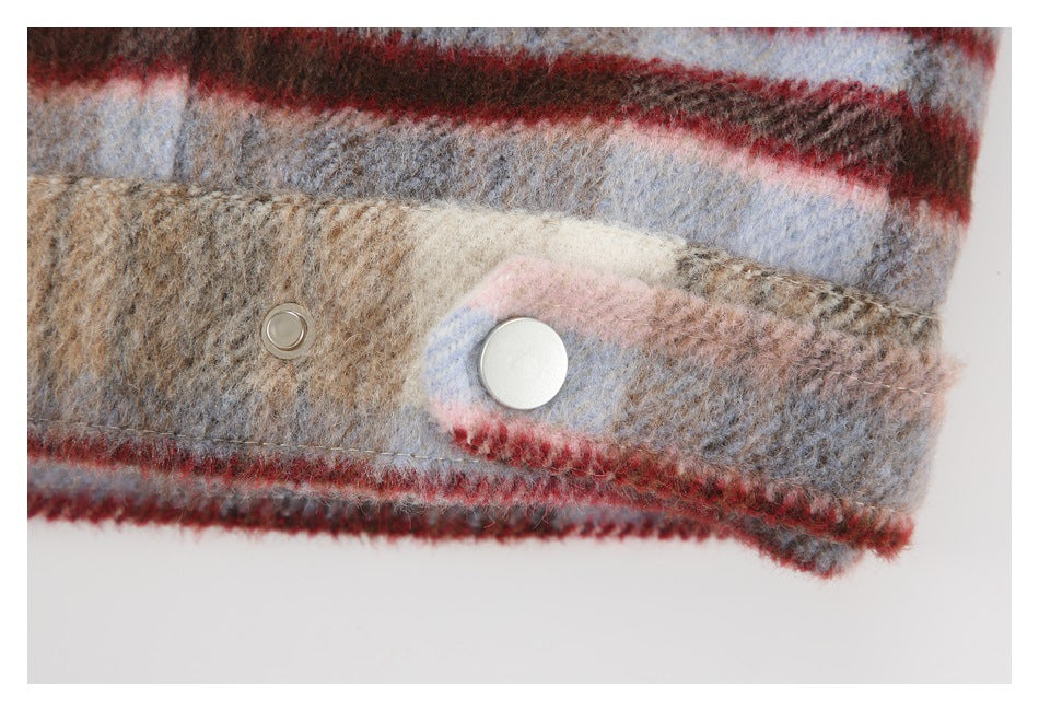 Close-up of a plaid garment cuff with a silver snap button and matching fabric-covered edge.