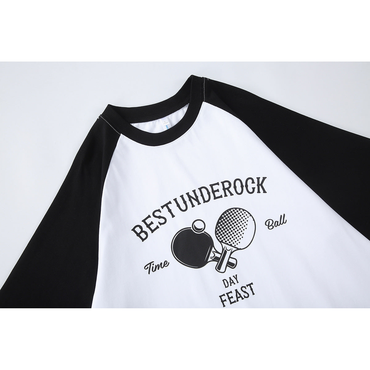 Front view of a white T-shirt with black raglan sleeves and a black ping-pong graphic with English lettering.