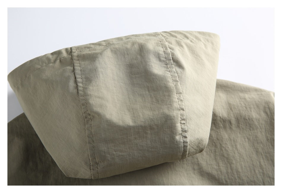 Close-up of the khaki jacket's hood, showing stitched panels and a subtle grid texture.