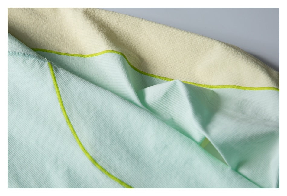 Close-up of mint and pale yellow garment panels with lime piping and seam details.