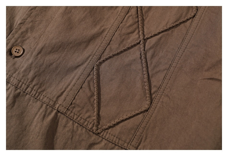 Close-up of the brown shirt's raised geometric stitching, seam, and a brown button.