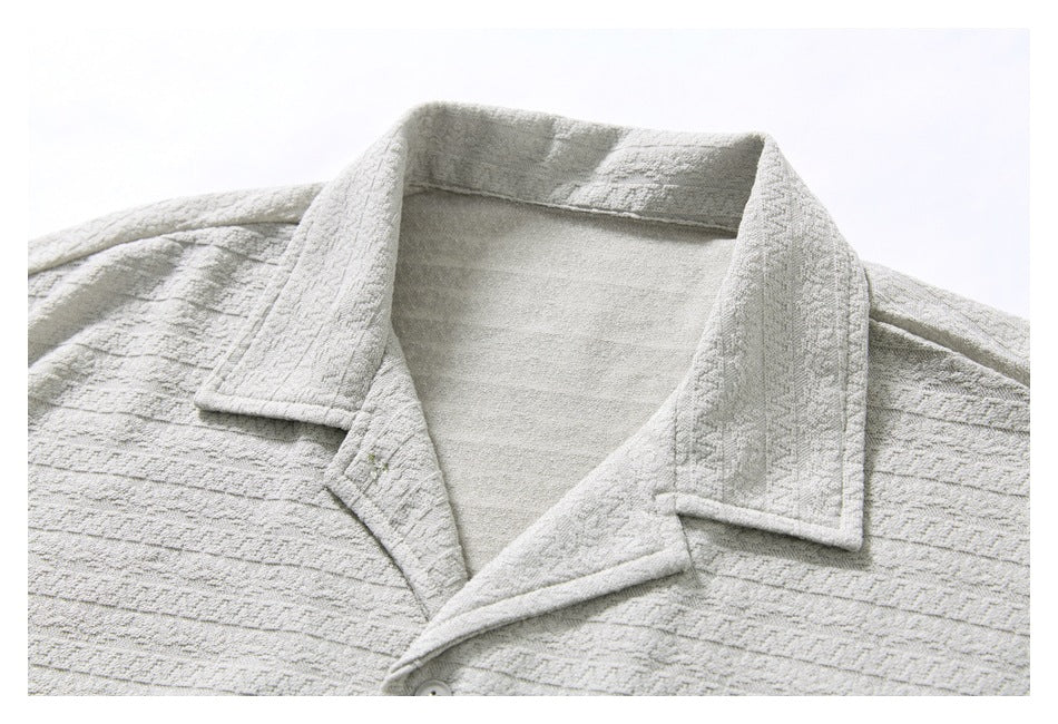 Close-up of a light gray shirt's notched collar, inner neckline, and patterned fabric.