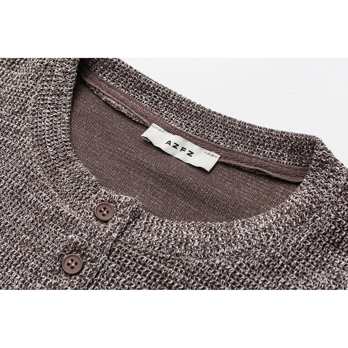Close-up of a brown-and-cream knit Henley neckline with two brown buttons and a sewn-in label.