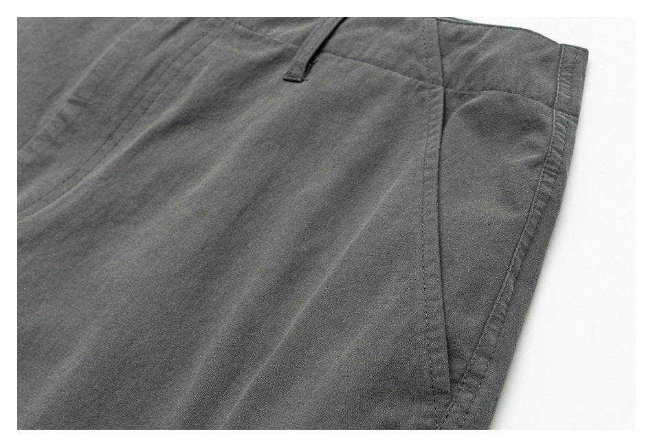 Close-up of charcoal-gray trousers showing a side seam, belt loop, and curved pocket opening.