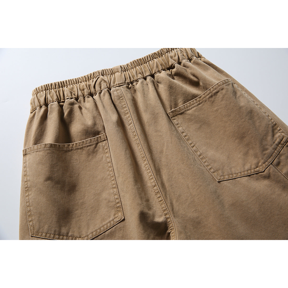 Close-up of the tan trousers' back waistband and two large patch pockets.
