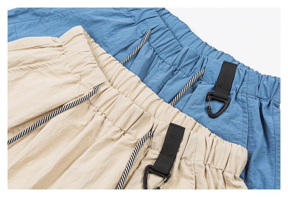Close-up of beige and blue pants waistbands with striped drawcords and black clip straps.