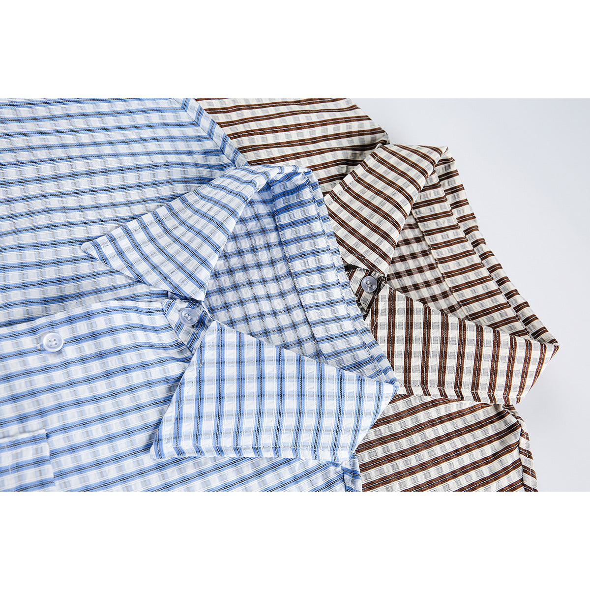 Overlapping blue and brown plaid short-sleeve button-up shirts shown close up with collars and buttons visible.