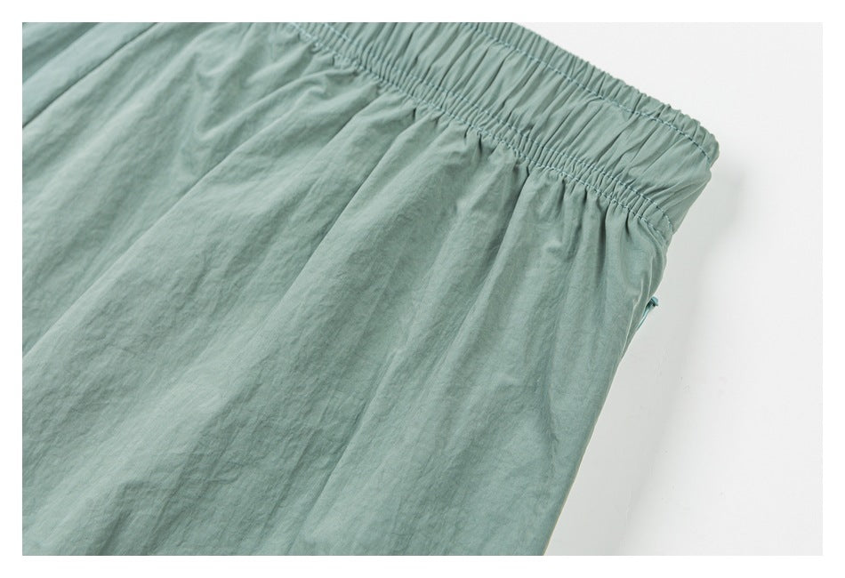 Close-up of the gathered elastic waistband and stitching on sage green shorts.