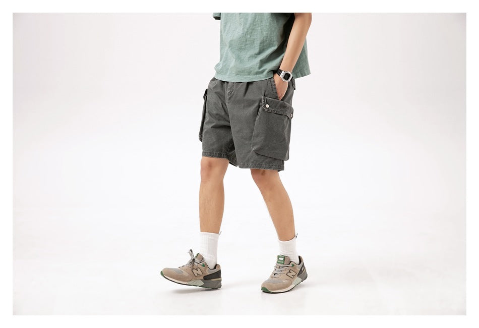 Model wearing charcoal gray cargo shorts with large flap pockets, shown from a three-quarter front angle.