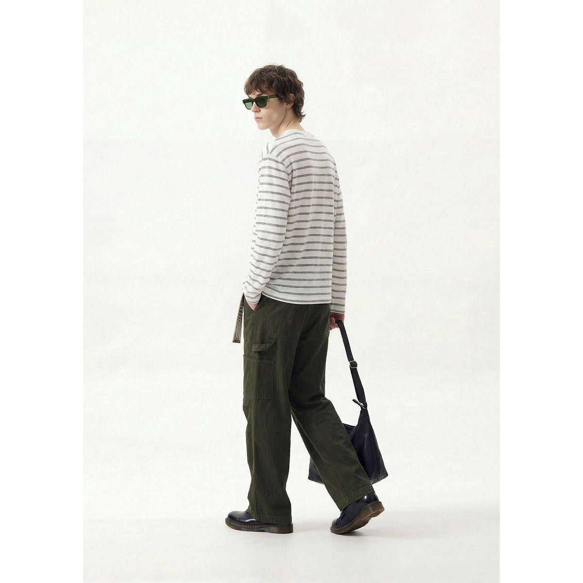 Model turned to show the back and side of a white and gray striped henley with dark olive cargo pants.