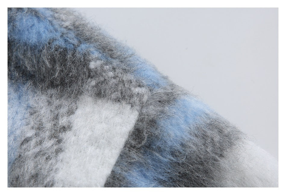 Extreme close-up showing the fuzzy blue, gray, and white plaid surface of the jacket.