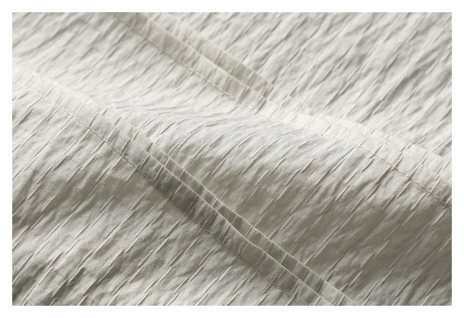 Close-up of pale ivory crinkled fabric and parallel stitched seams.