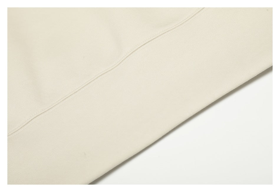 Close-up of a stitched seam and hem on the cream hoodie.