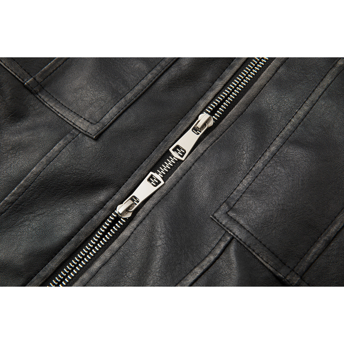 Close-up of the black jacket's silver double zipper and stitched chest pockets.