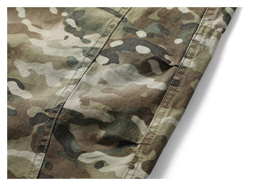 Close-up of a stitched side seam on green-brown camouflage garment fabric against a white background.