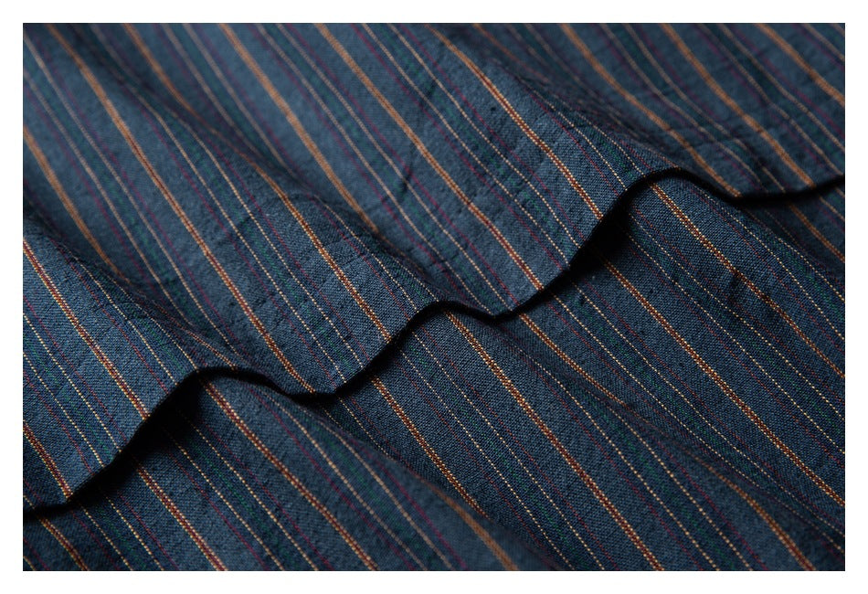 Close-up of dark blue fabric with thin multicolor stripes, draped to show its surface and folds.