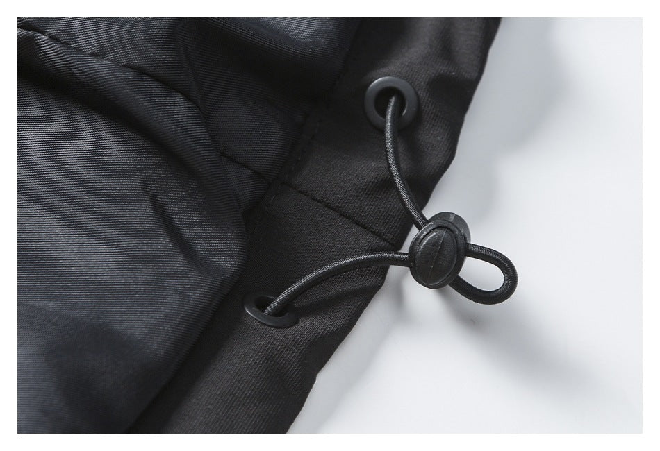 Close-up of a black garment's adjustable elastic cord and toggle threaded through metal eyelets.