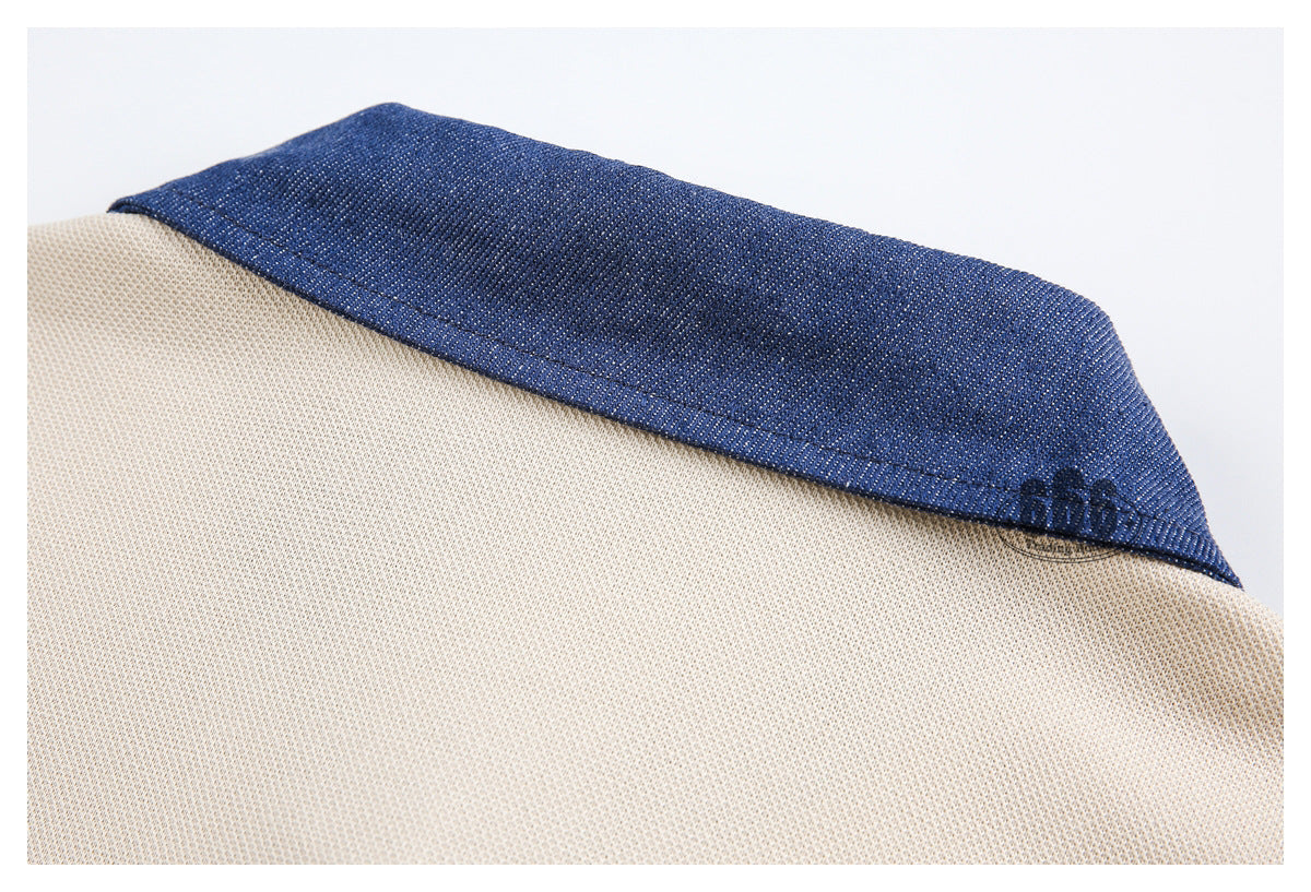 Close-up of a cream knit garment with a contrasting dark blue collar and a small dark embroidered mark.
