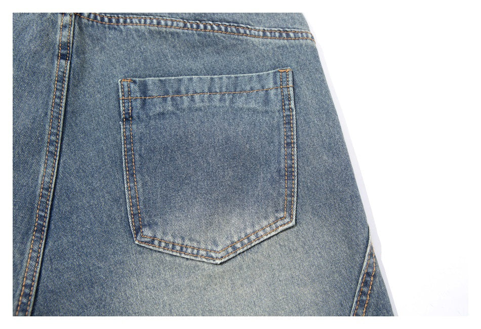Close-up of a stitched patch pocket on the back of blue denim pants.