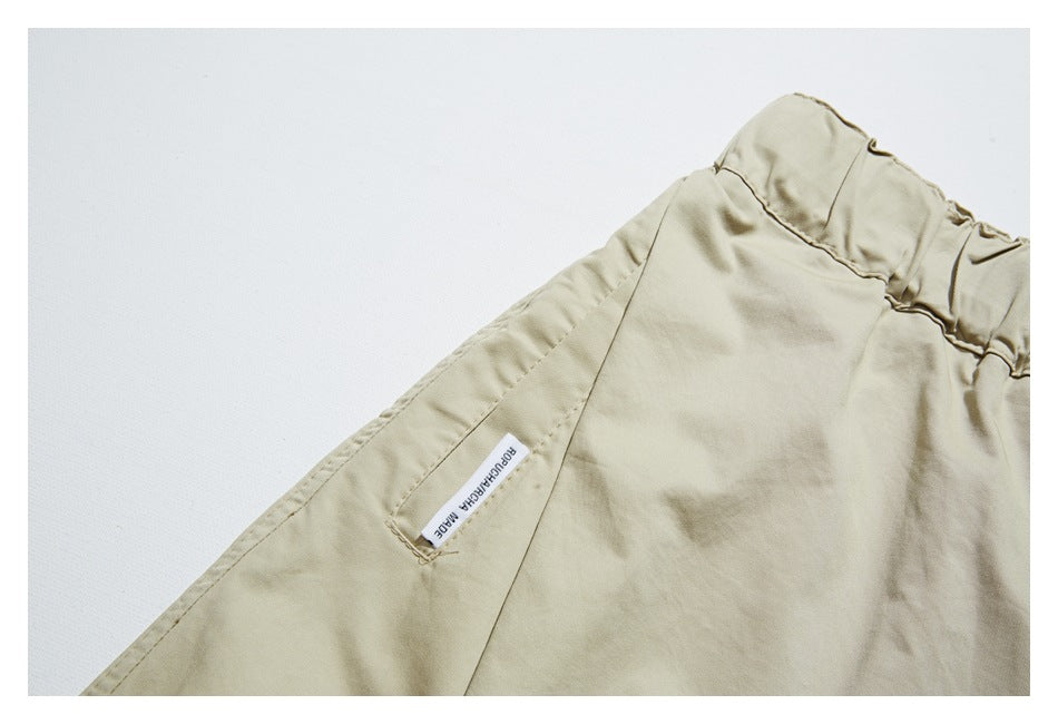 Close-up of a beige garment with a seam and a small white woven label.