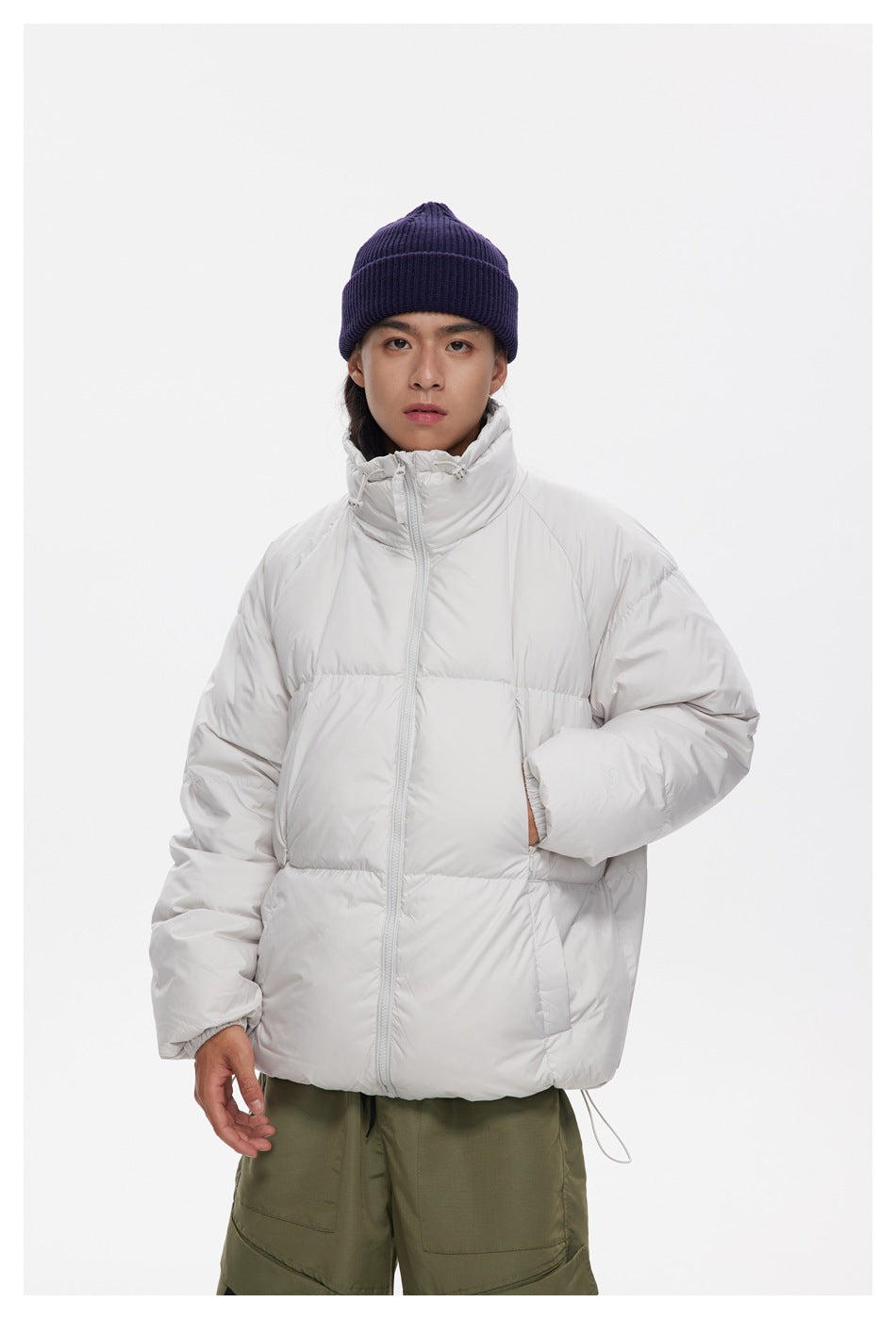 Closer view of a model wearing a white quilted puffer jacket zipped to its high collar.