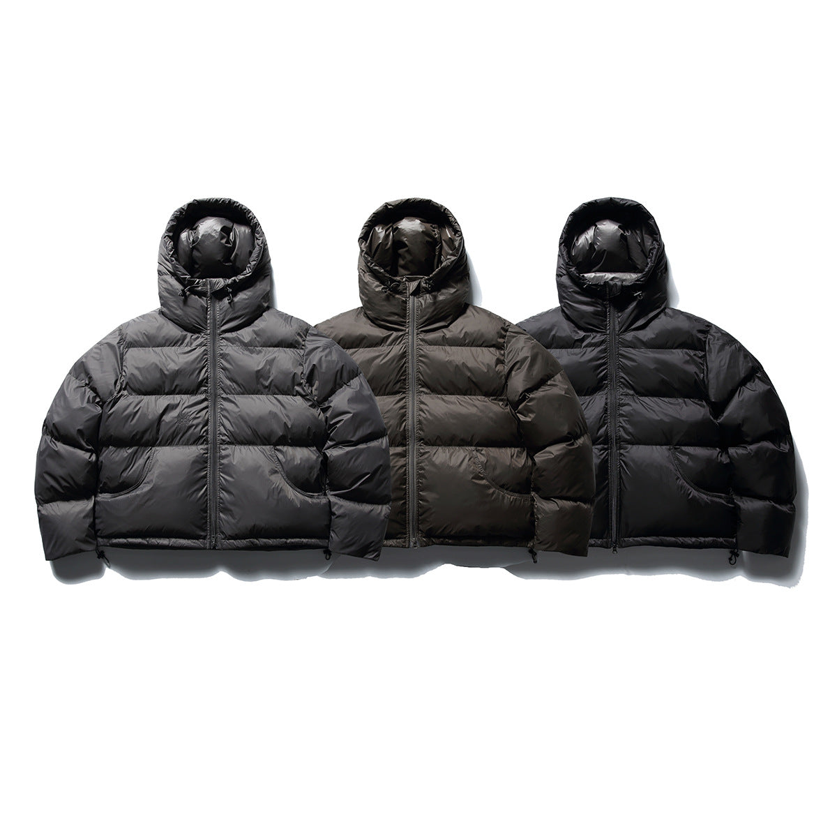 Three hooded quilted jackets shown together in gray, dark brown, and black, each with a front zipper and pockets.