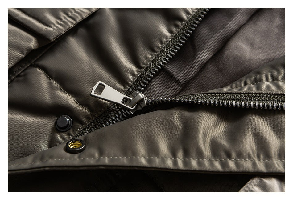 Close-up of a charcoal-olive garment front with a metal zipper, snap fasteners, and stitched placket.