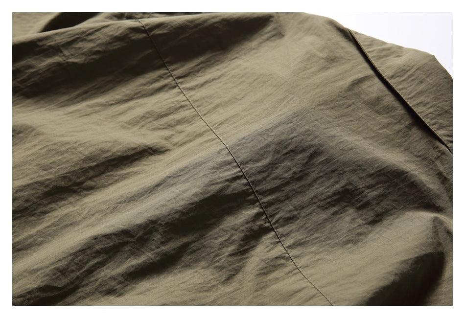 Close-up of olive-brown shirt fabric and a diagonal seam.