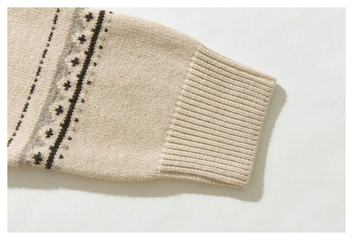 Close-up of a cream cardigan sleeve ending in a wide ribbed cuff beside a dark geometric knit band.