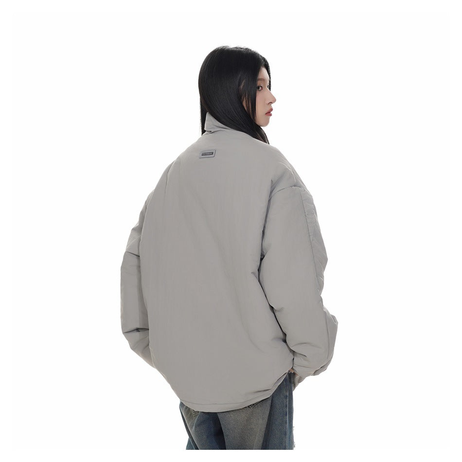 Model in a light gray oversized padded jacket, shown from the back with a small label near the collar.