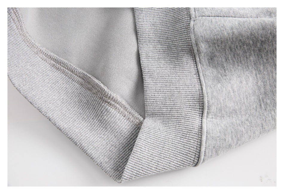 Close-up of the hoodie’s inside seam and wide ribbed waistband in light gray.