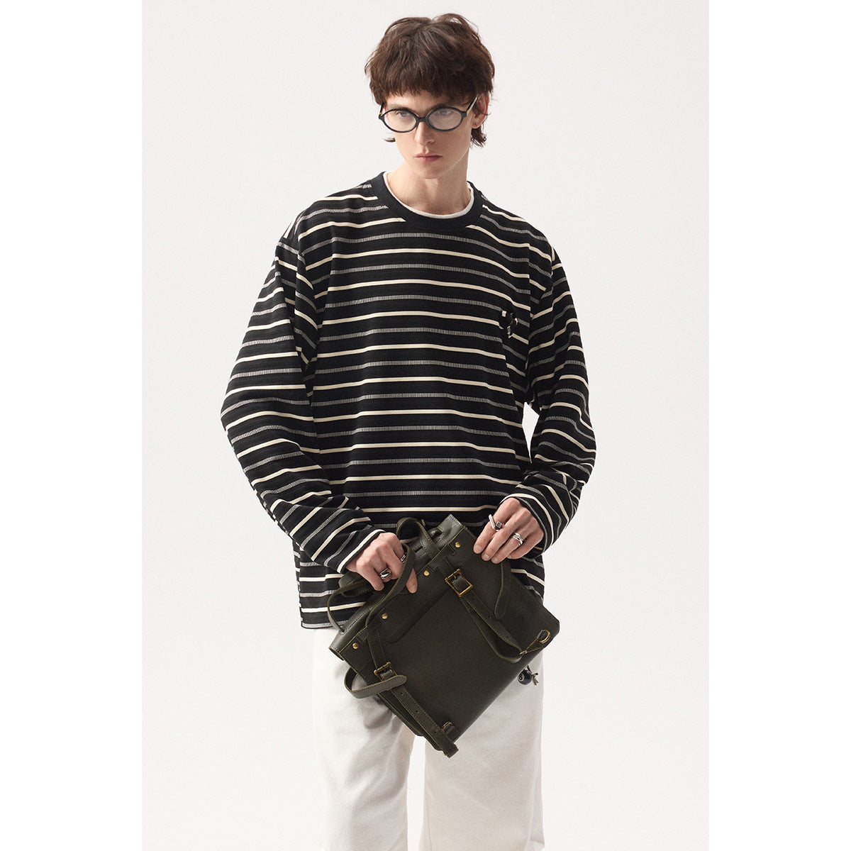 Model wearing a black long-sleeve shirt with thin cream horizontal stripes and a small chest detail.