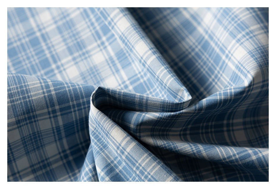 Blue and white plaid fabric shown in a close-up with sculpted folds and shadows.