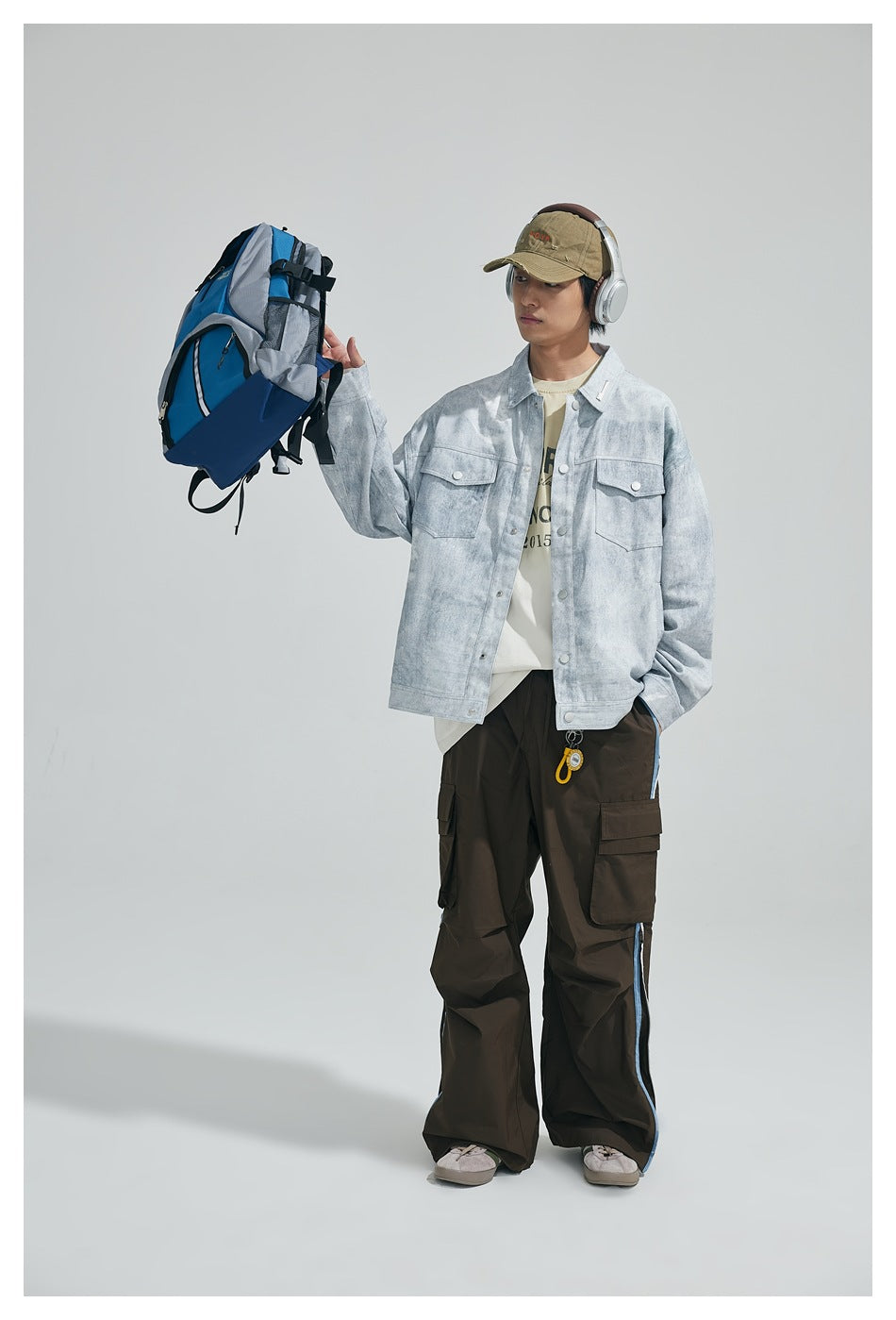 Full-length model view of a light gray mottled snap-front jacket with flap chest pockets and a relaxed fit.