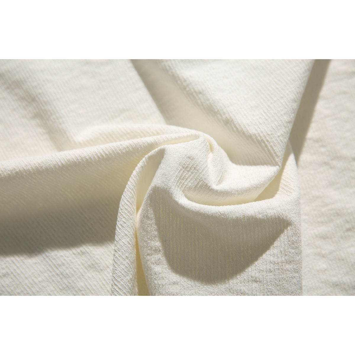 Close-up of cream ribbed-looking fabric gathered into folds.