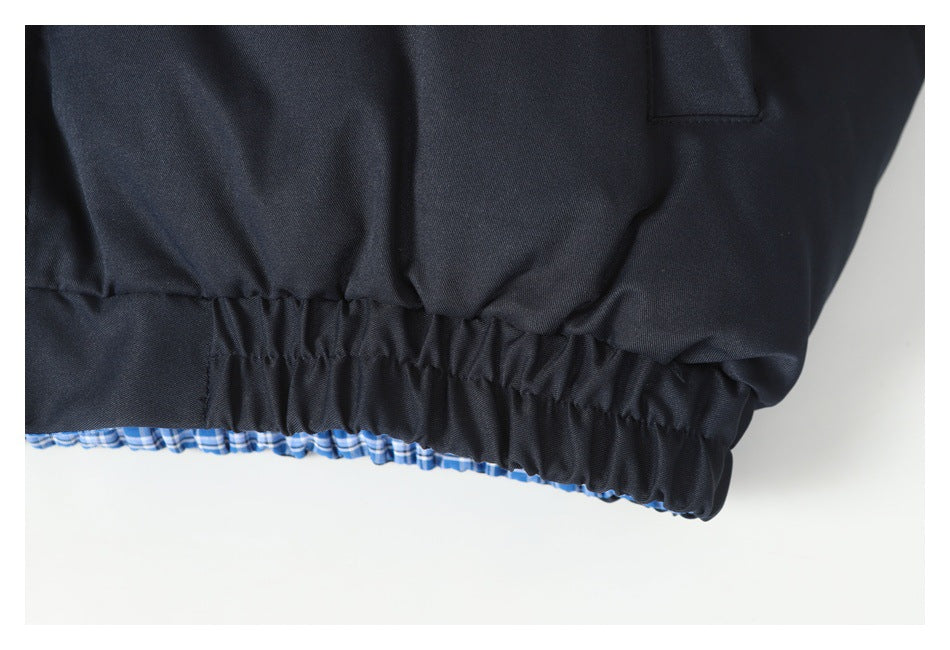 Close-up of a dark navy jacket's gathered hem with blue plaid lining peeking out.