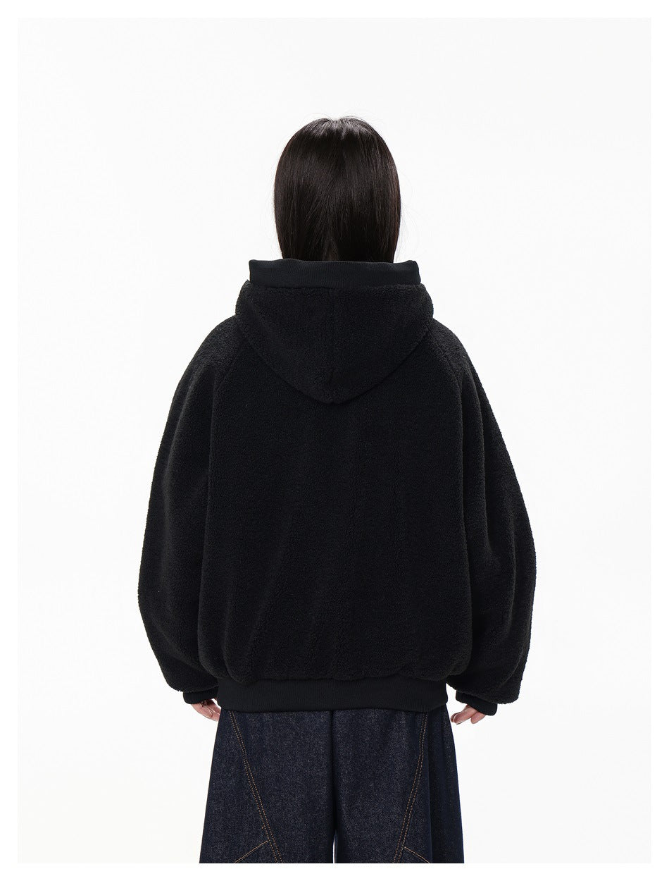 Back view of a model wearing a black plush hooded jacket with ribbed cuffs and hem.