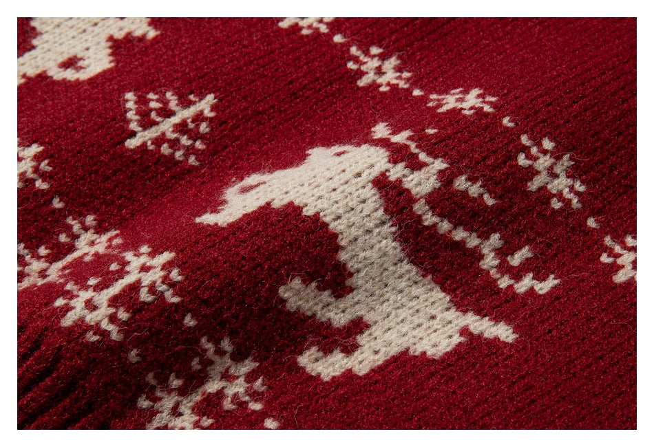 Close-up of a deep red knit with a cream reindeer and scattered snowflake motifs.