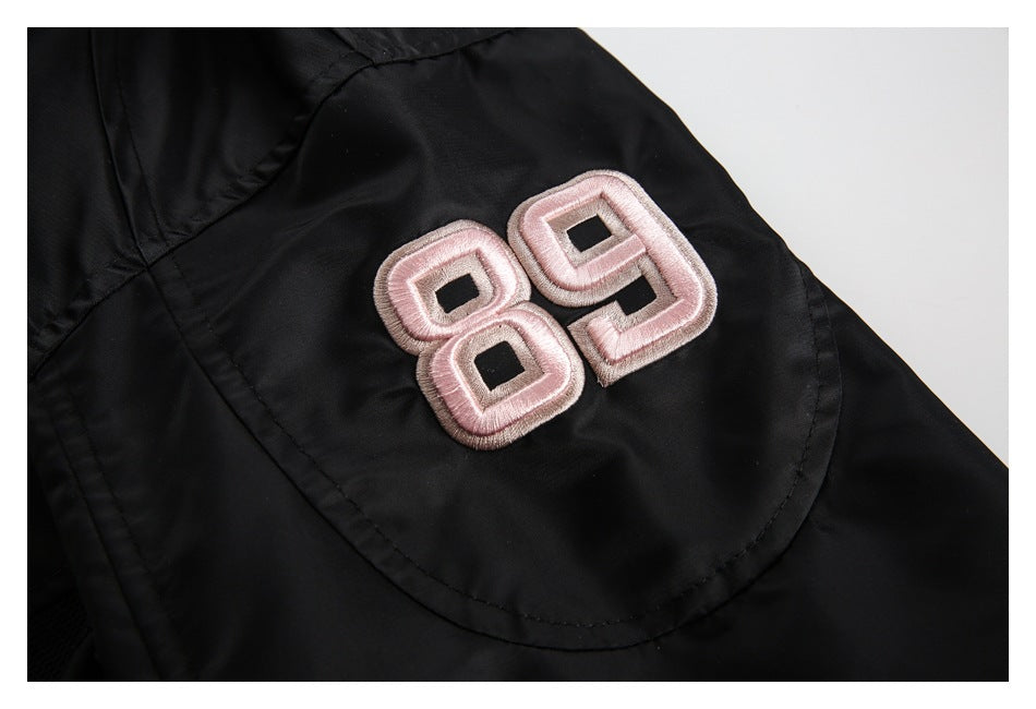 Close-up of a raised pale pink 89 patch on the black jacket sleeve.